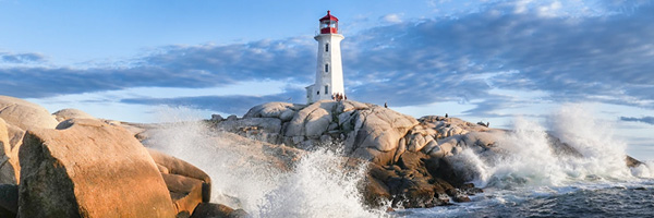 A lighthouse stands on rocky cliffs as waves crash against its base, highlighting the power of the ocean.
