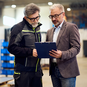 Two people reviewing a clipboard in an industrial setting.