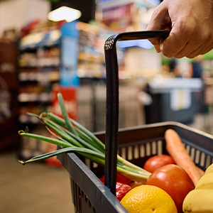 A shopper holding a grocery basket at the grocery store.