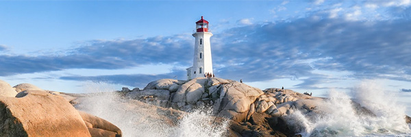 Lighthouse on rocky shore with waves crashing