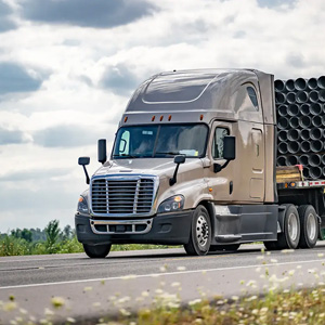 A semi truck transporting large pipes on a highway