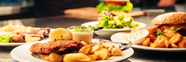 Plates of restaurant meals including fries, meat, and a burger.