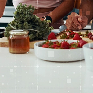 Person preparing fruit and greens on a kitchen counter.