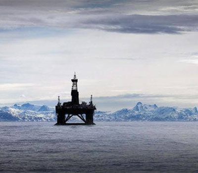 Offshore oil rig in Arctic Ocean with icy landscape in the background